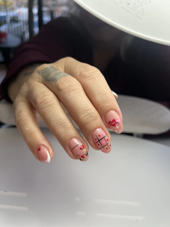 Unghie corte con nail art di cuori rossi e tris